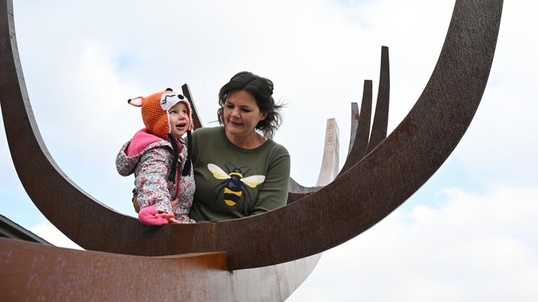 Mother and daughter by the contemporary full-size sculpture of an Anglo-Saxon ship at Sutton Hoo, Suffolk
